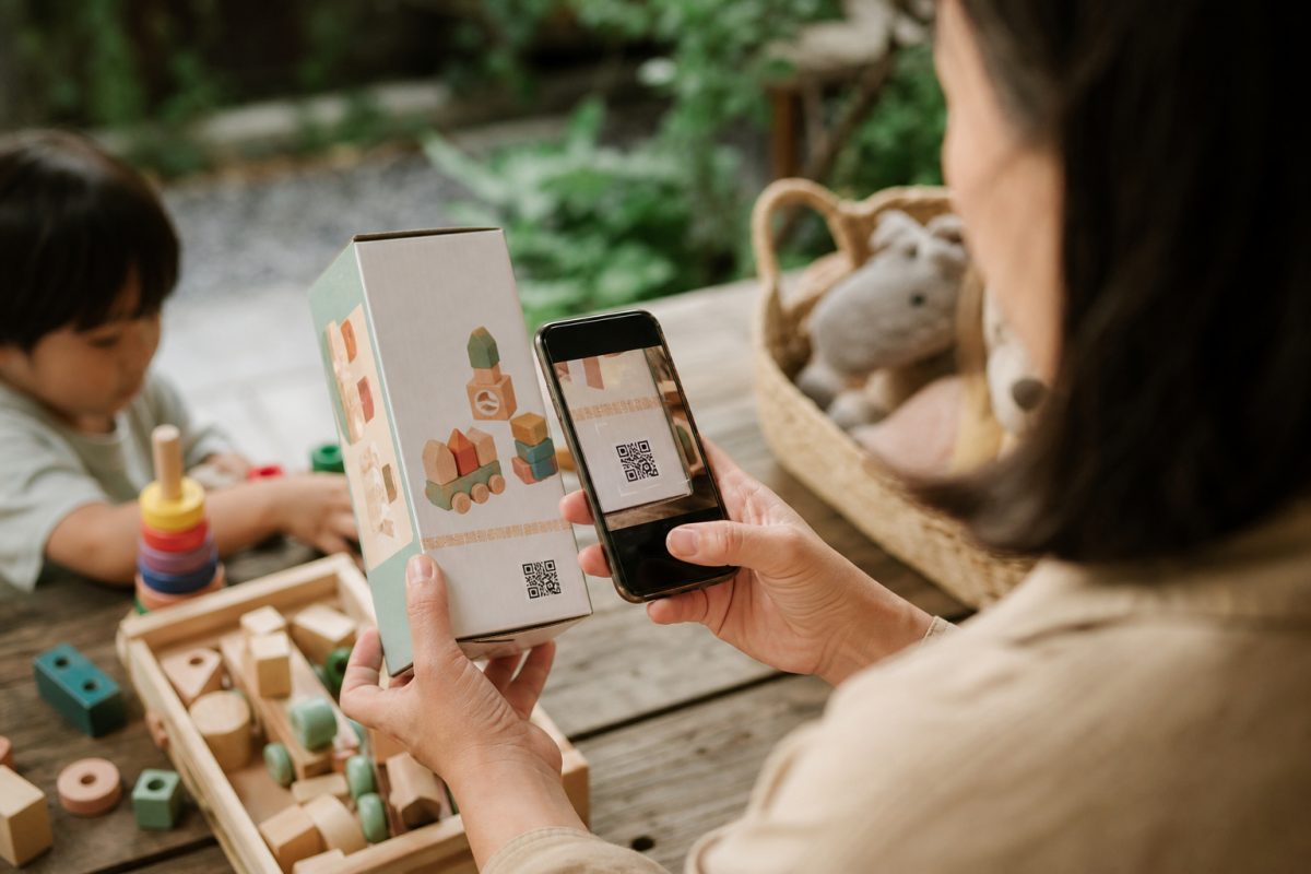 Szülő digitális termékútlevelet ellenőriz egy játék dobozán