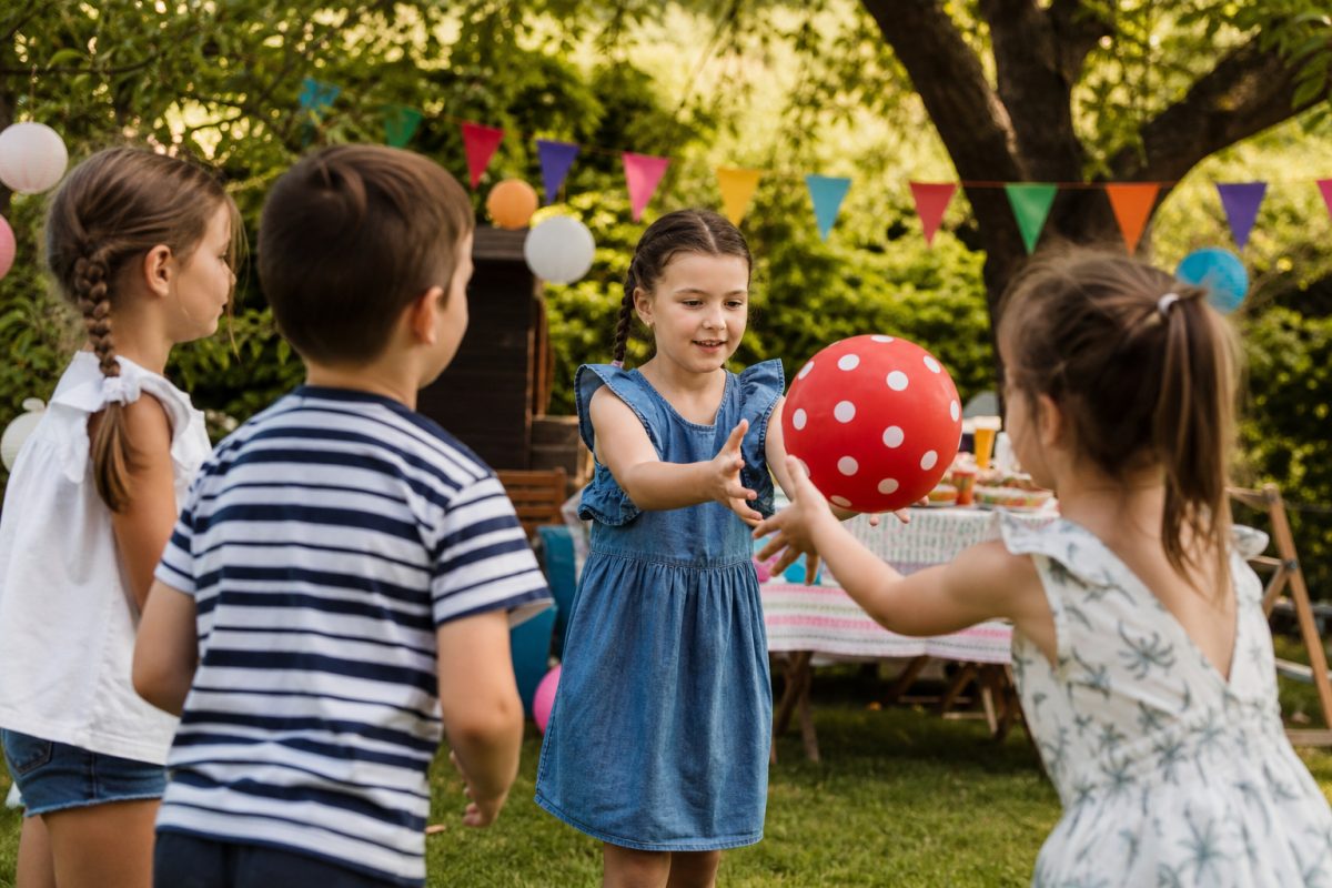 Gyerekek pöttyös gumilabdával játszanak kerti zsúron
