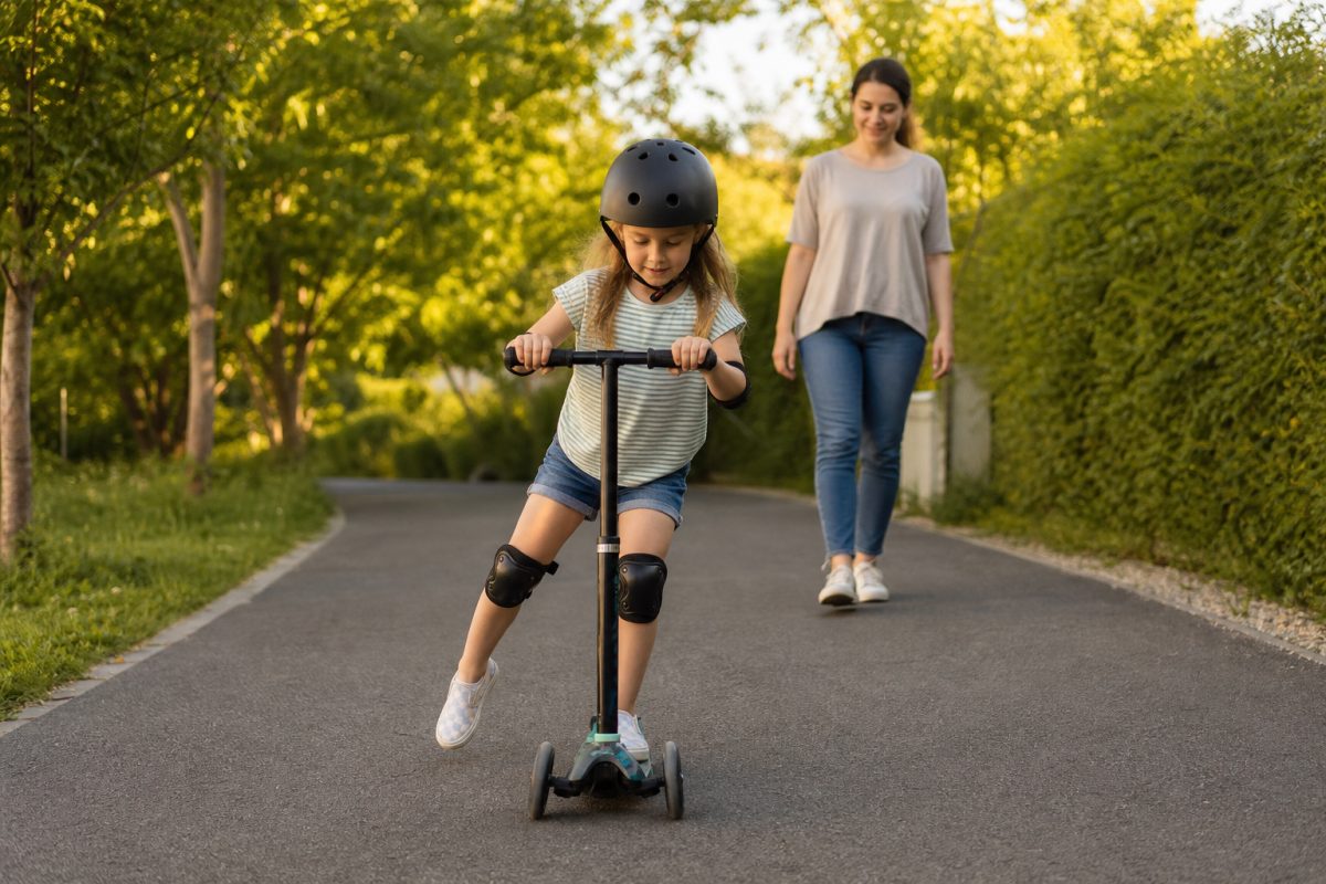 Gyerek sisakban fékezést gyakorol háromkerekű rollerrel