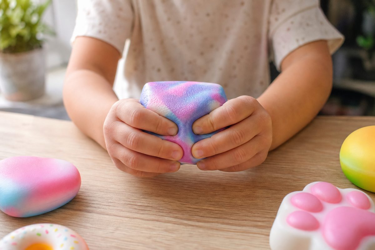 Gyerekkéz puha squishy kockát nyomkod az asztalnál